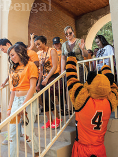 Students walking through the arch while Benny cheers them on
