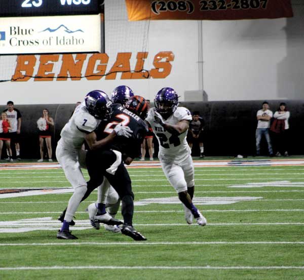 Three opposing team players tackle ISU player.