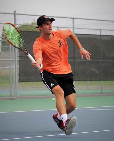 Gary rendek holds racket and prepares to hit tennis ball.