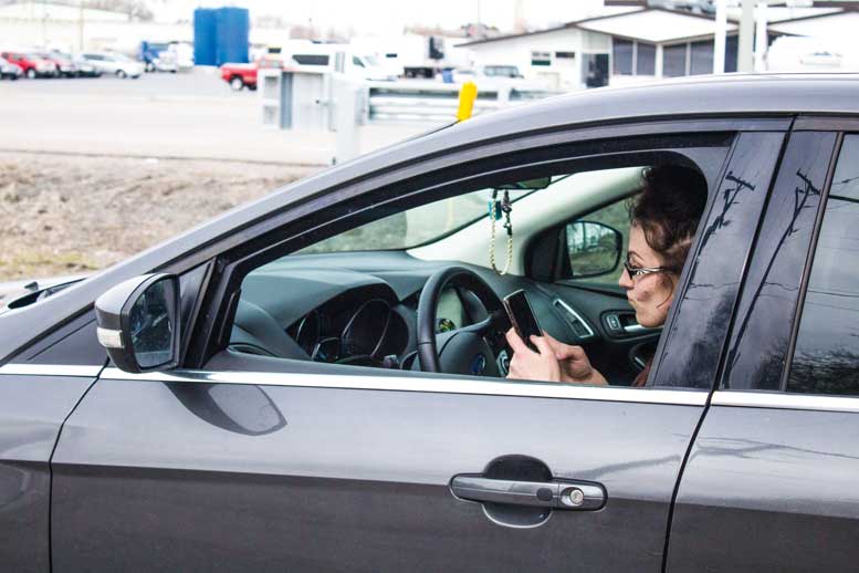 Woman sits in driver's seat of car, texting