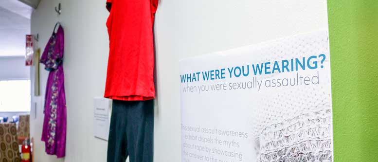 Two outfits hang on wall as part of the "What Were You Wearing?" exhibit