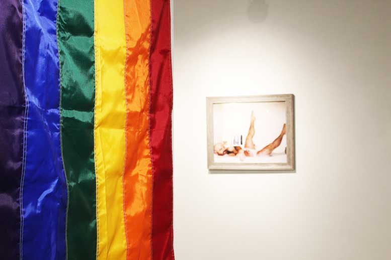 Rainbow flag in front of portrait on wall