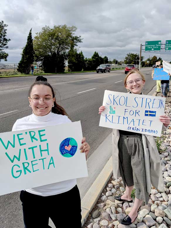 Two women stand by the road, holding signs