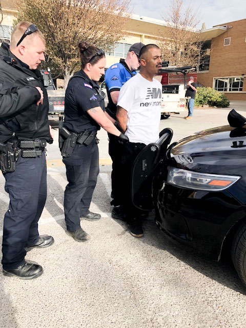 Police officers arrest Chavez against a car