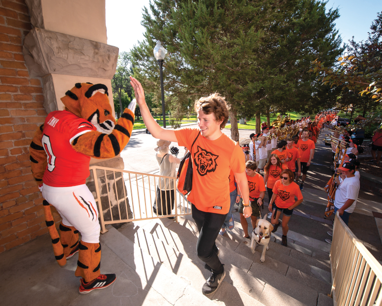 ISU student high fives Benny the Bengal as he marches through the arch.