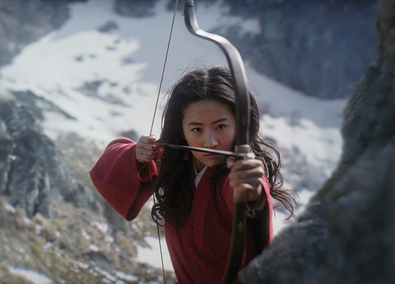 Mulan draws back bow and arrow standing behind a rock