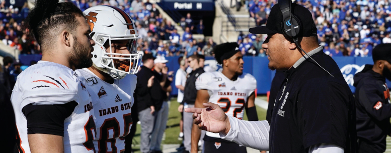 Two football players talk to coach.