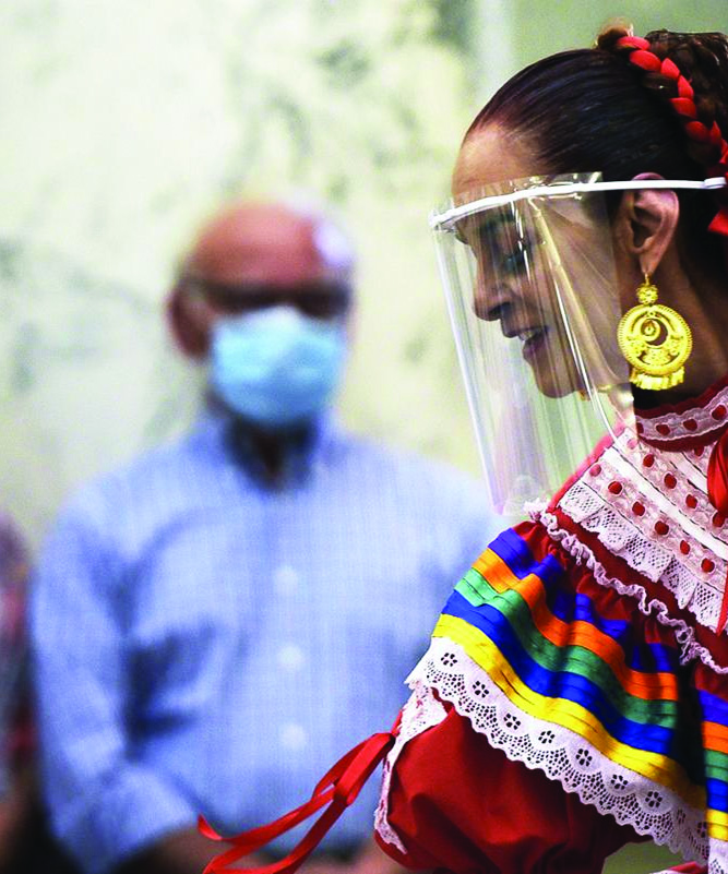 Woman in traditional hispanic dress with face shield