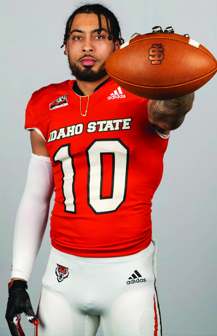 Isaiah Walters in football uniform holds football out towards camera.