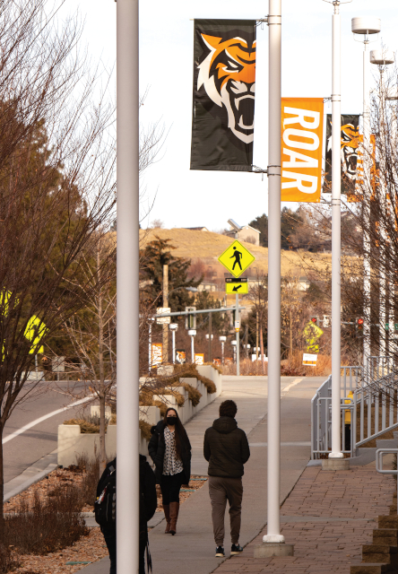 Masked students walk on sidewalk on campus