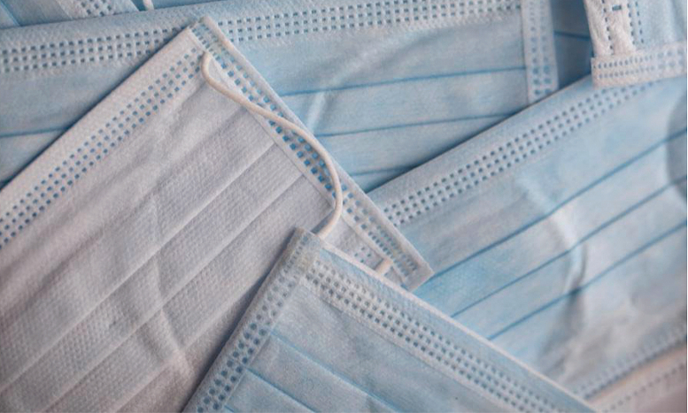 Layered pile of blue surgical masks