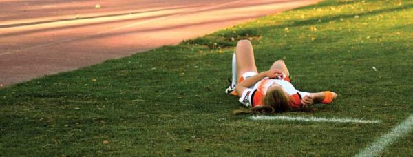Soccer player lays on grass.
